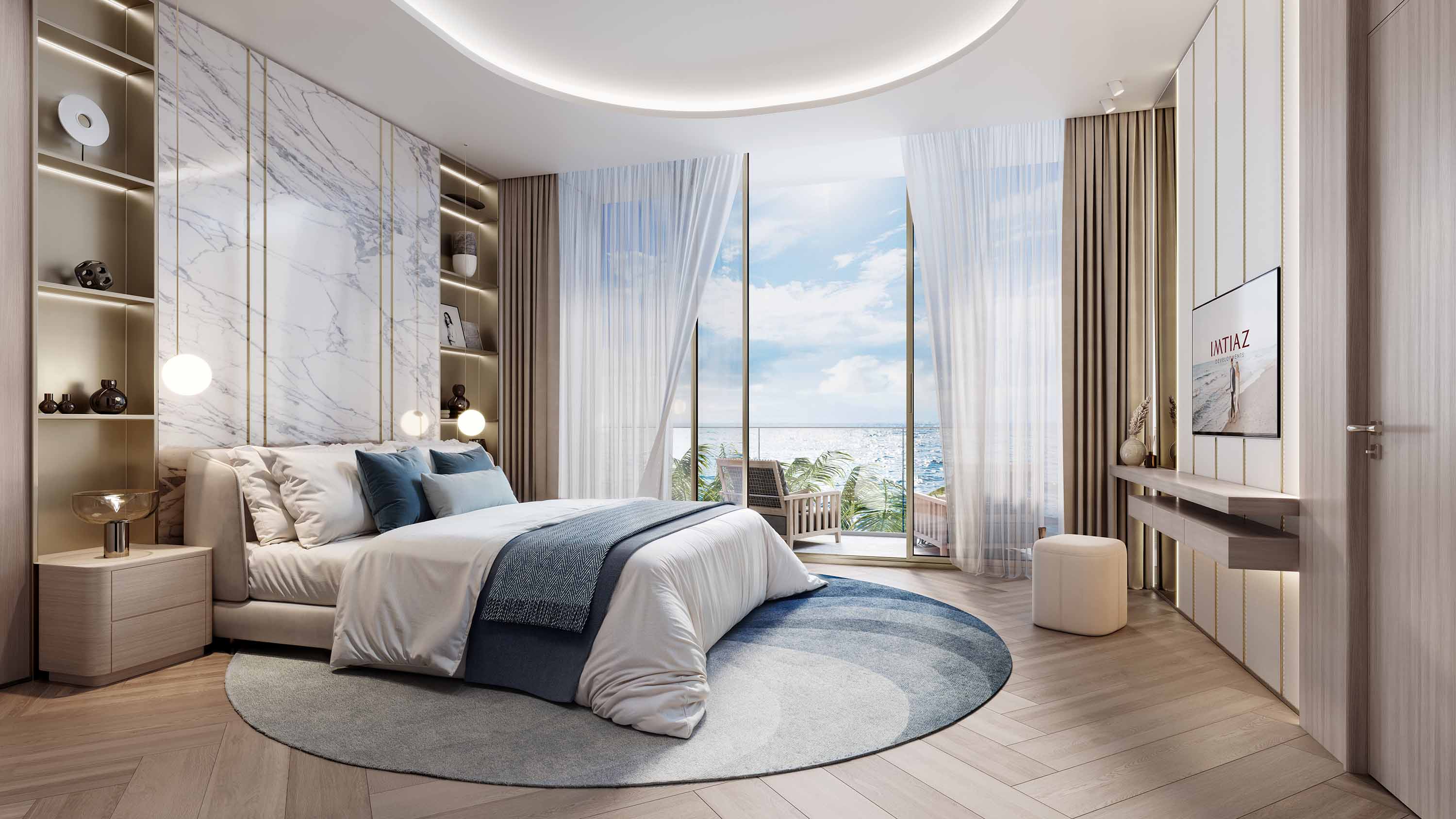 Sunset Bay By Imtiaz A modern bedroom featuring a large bed, round rug, and a view of the sea through expansive glass doors.